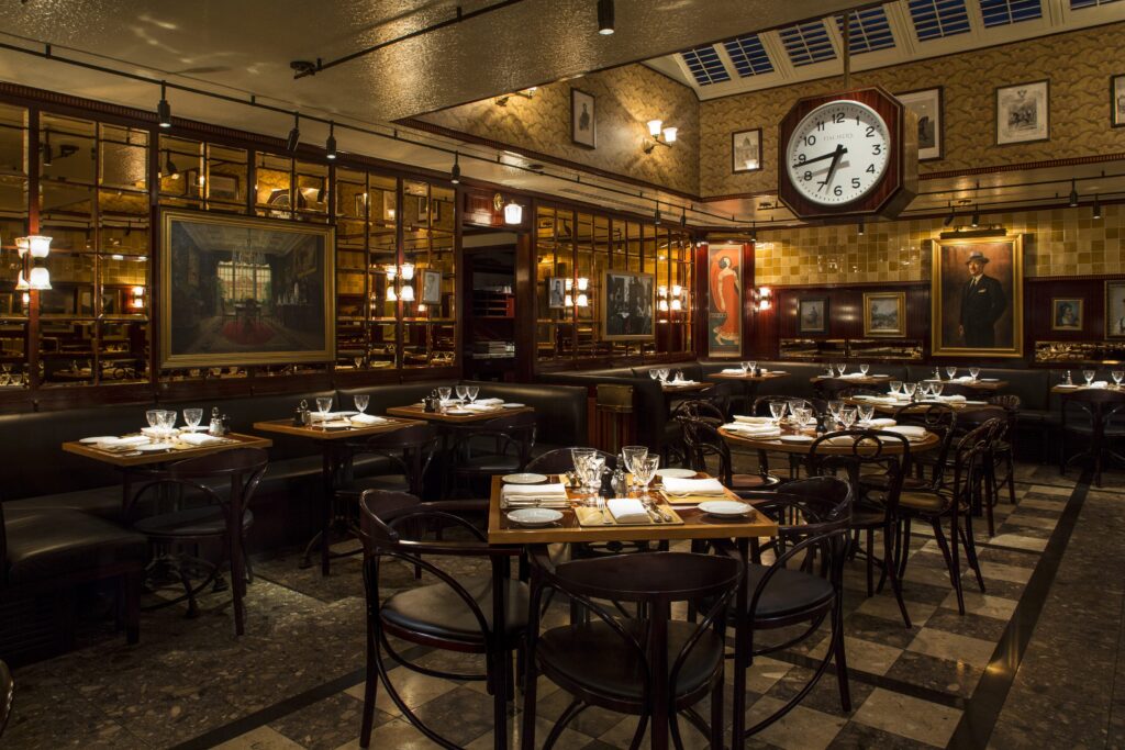Fischer's interior with many set tables, yellow decor and soft lighting with large clock hanging from the roof